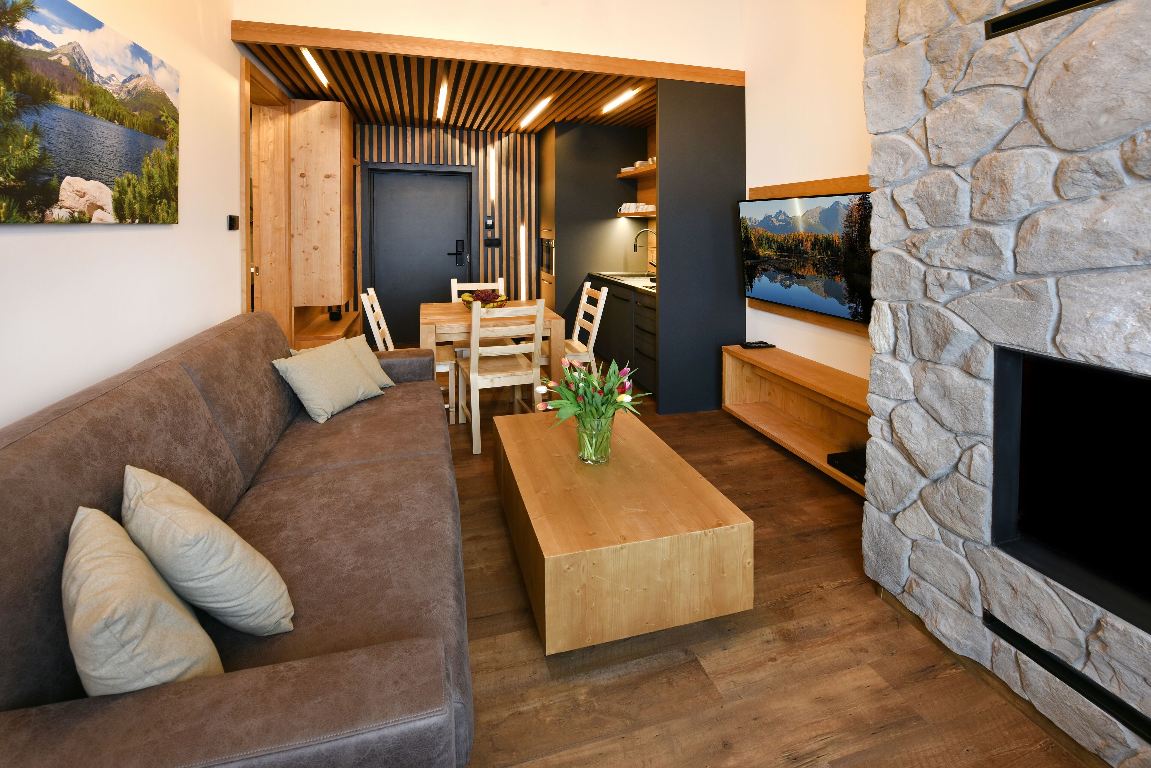Ein modernes Wohnzimmer mit einem braunen Ledersofa, einem Holztisch und einem Kamin aus Stein.