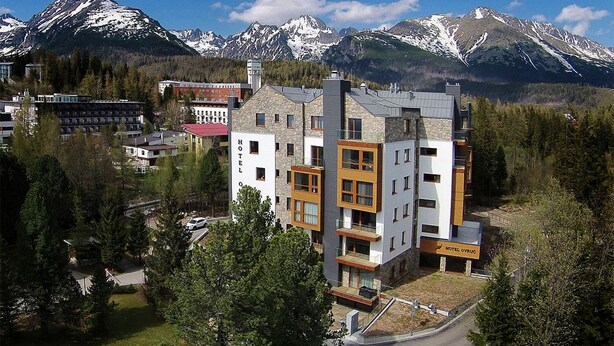 Un hotel de diseño moderno, con varios pisos y vistas a montañas nevadas al fondo.