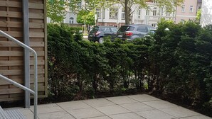 A paved courtyard with a metal staircase, dense green hedges, and parked cars in the background. - Central apartment in Magdeburg with Netflix and kitchen WE18 (Magdeburg)