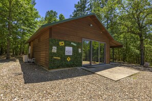 Escape to a secluded cabin surrounded by trees, with an outdoor area and a large sliding glass door.