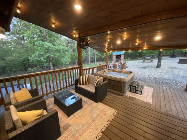 Relax in a serene outdoor space with a hot tub, wicker furniture, and a forest view.