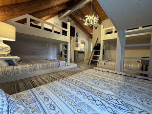 Cozy bedroom with two bunk beds, a ladder, and a chandelier.