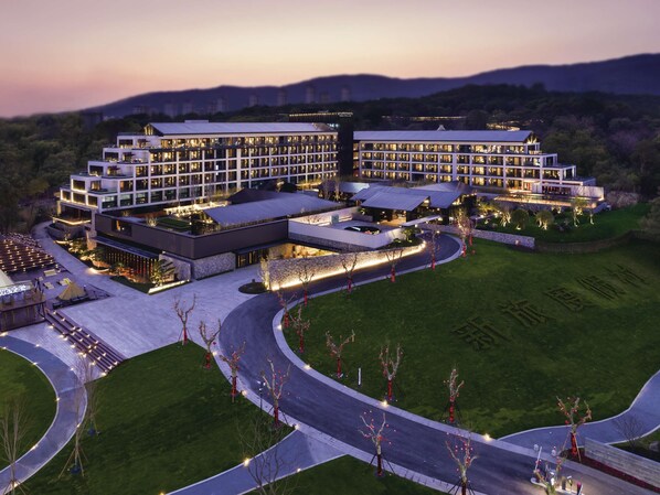 Un hotel grande y moderno con varias edificaciones, un césped cuidado y un camino de entrada curvo.