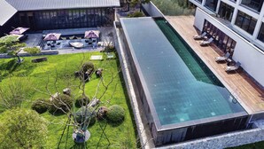 Un hotel moderno con piscina infinita en la azotea, zona de estar al aire libre y jardín bien cuidado.
