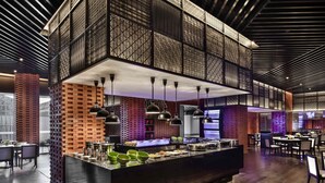 Un restaurante moderno con una isla central, detalles de ladrillo y lámparas colgantes.