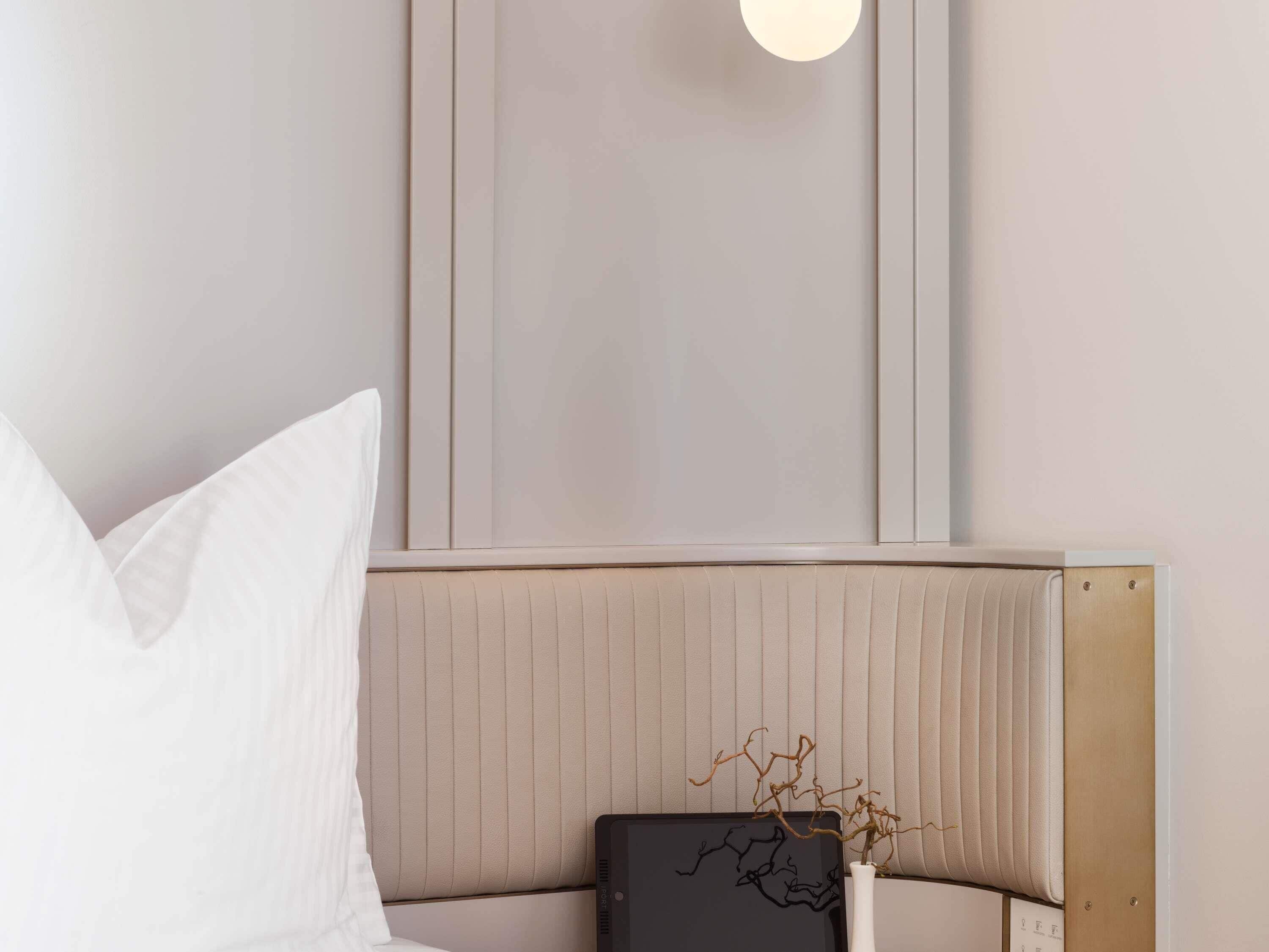 Een moderne kamer met een bed, een nachtkastje en een wandlamp.