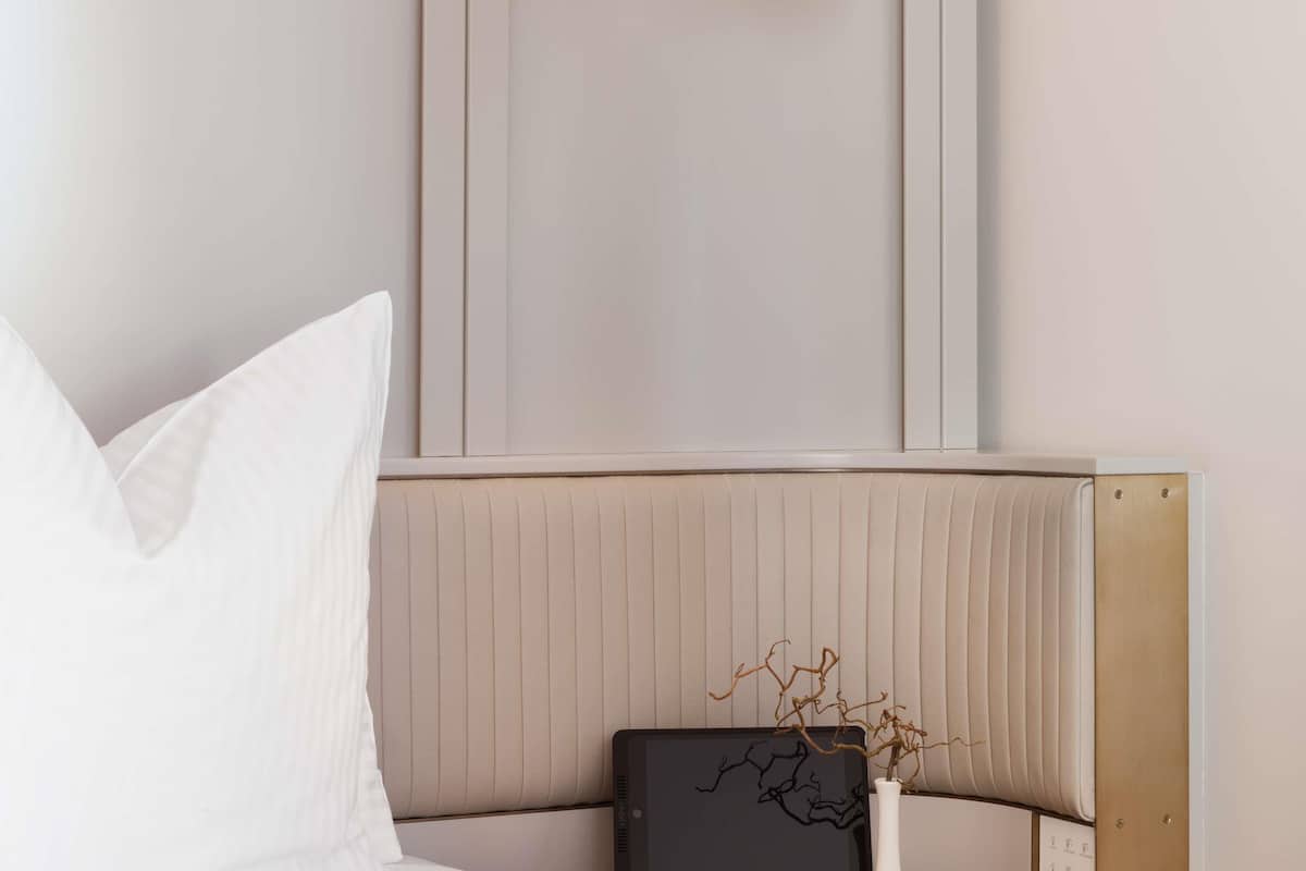 Een moderne kamer met een bed, een nachtkastje en een wandlamp.