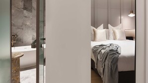 Une chambre à coucher moderne, avec un lit, une table de chevet et une salle de bain équipée d’un lavabo et d’un miroir.