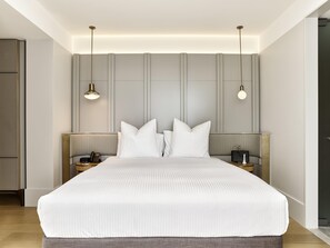 A modern hotel bedroom with a large bed, bedside tables, and pendant lighting.