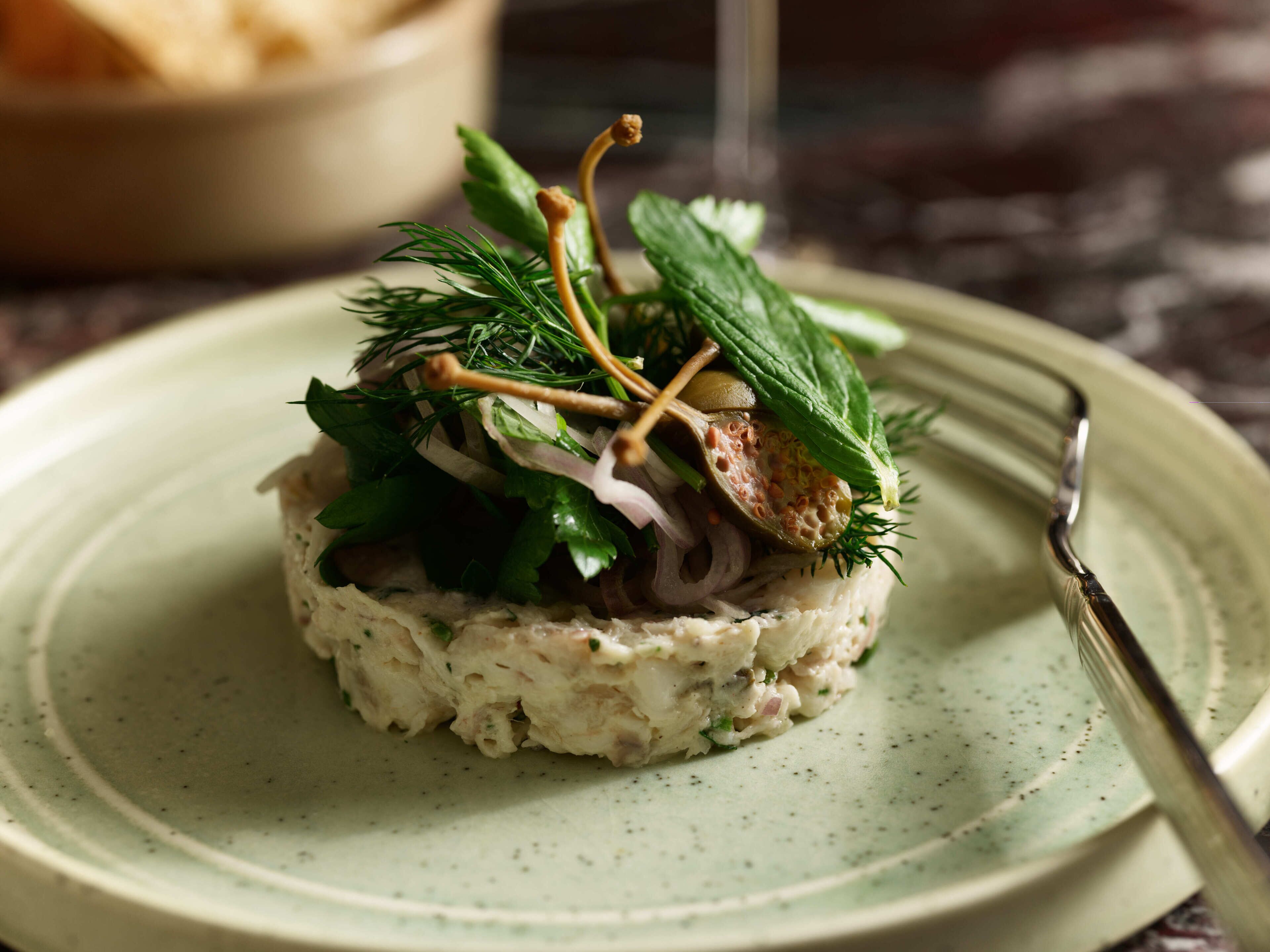 Un plato con un alimento en capas, adornado con hierbas y una ramita.