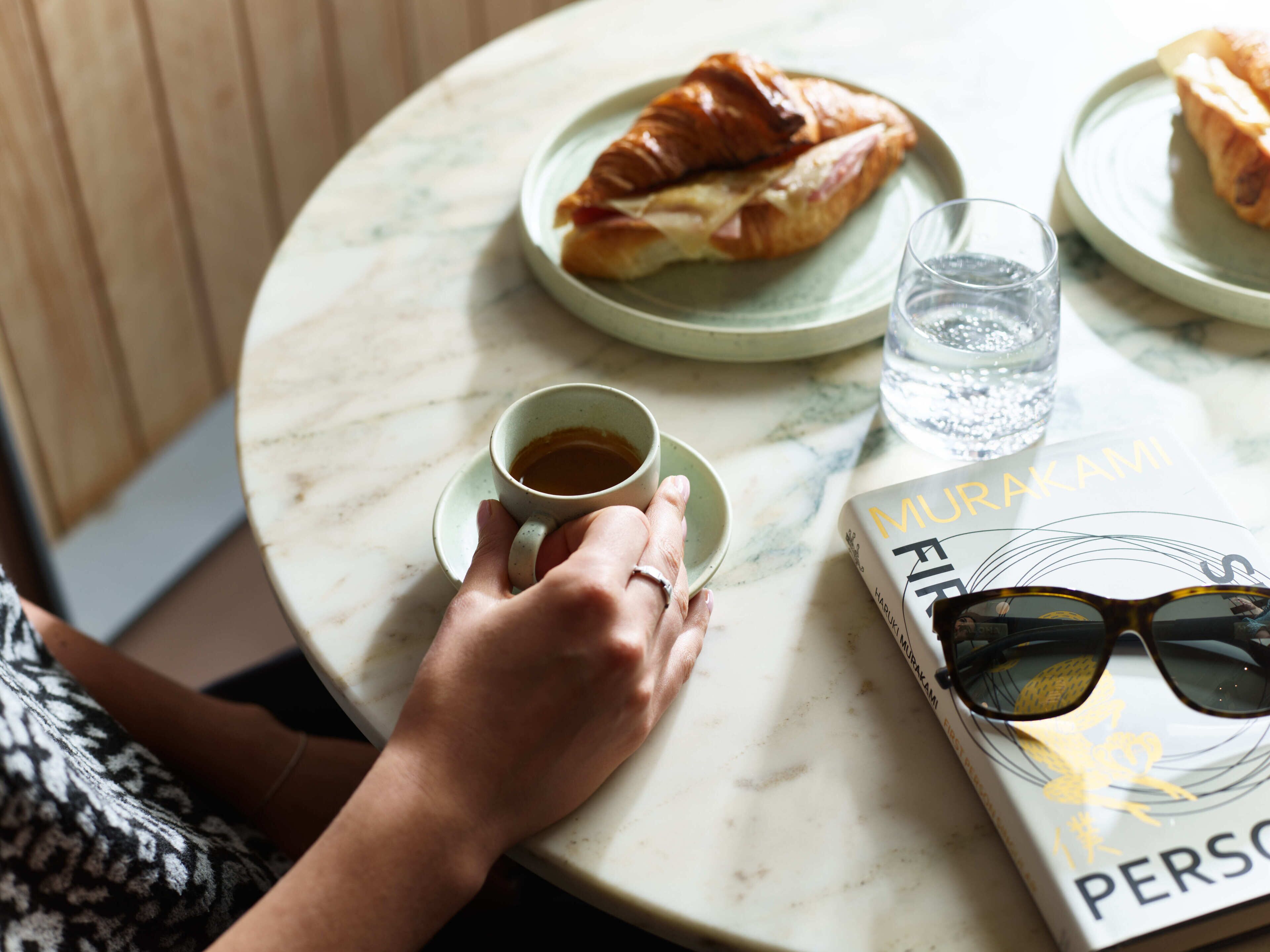 A round table with a book, a glass of water, and a cup of coffee.