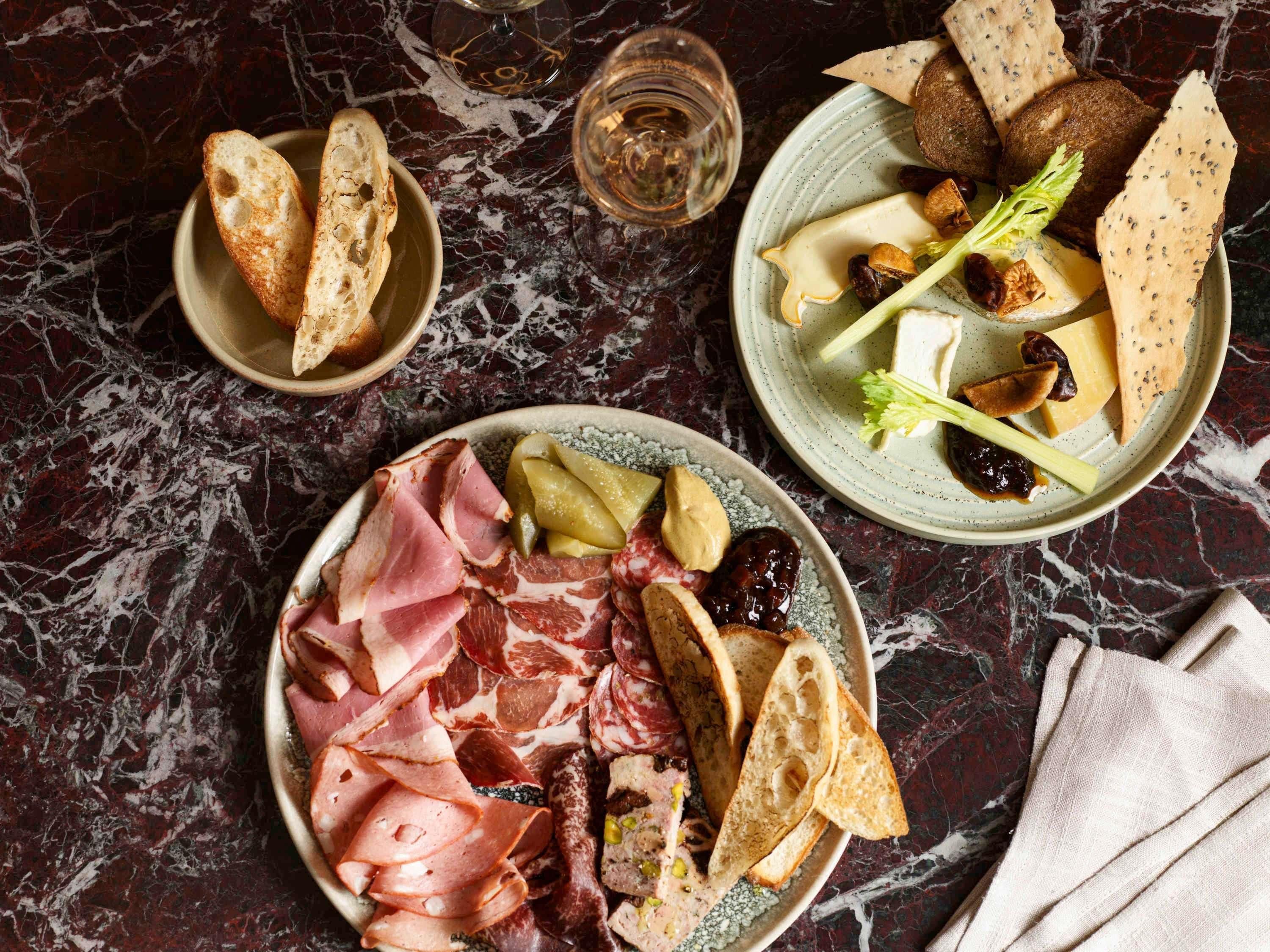 Ein Marmortisch mit Schinken, Käse, Nüssen und Brot.