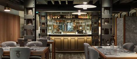 A restaurant with a bar area, wooden tables, and chairs.
