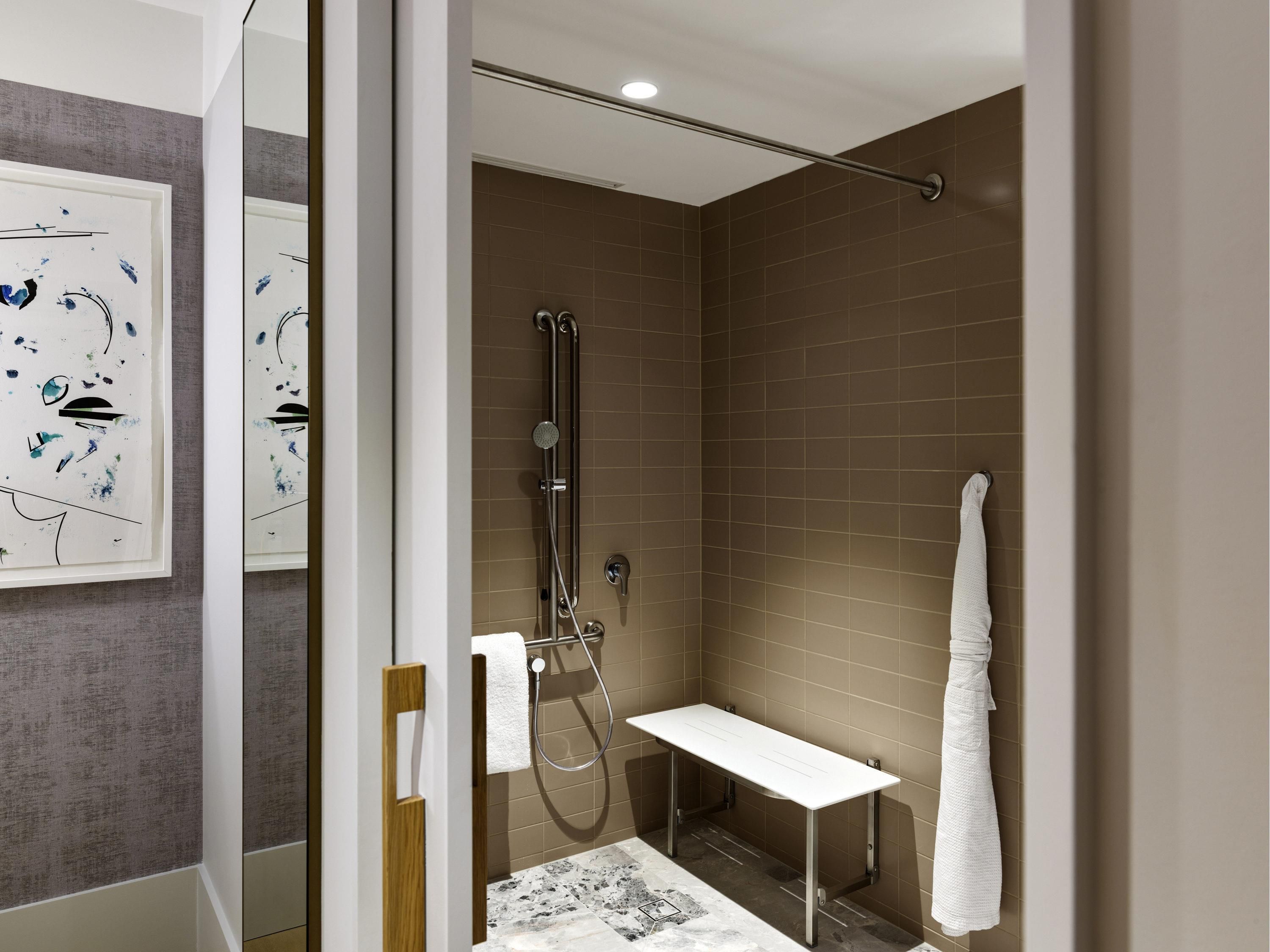 A modern bathroom with a shower, a white sink, and a towel rack.
