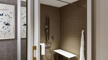 A modern bathroom with a shower, a white sink, and a towel rack.