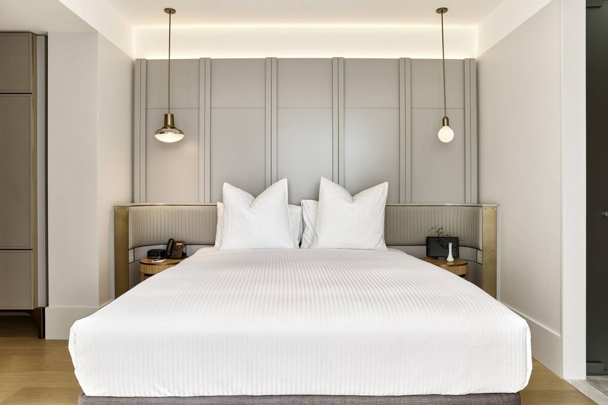 Ein modernes Hotelzimmer mit einem großen Bett, Nachttischen und Pendelleuchten.