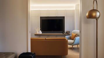 Una sala de estar moderna con un televisor de pantalla plana, un sofá, una silla y una lámpara de pie.