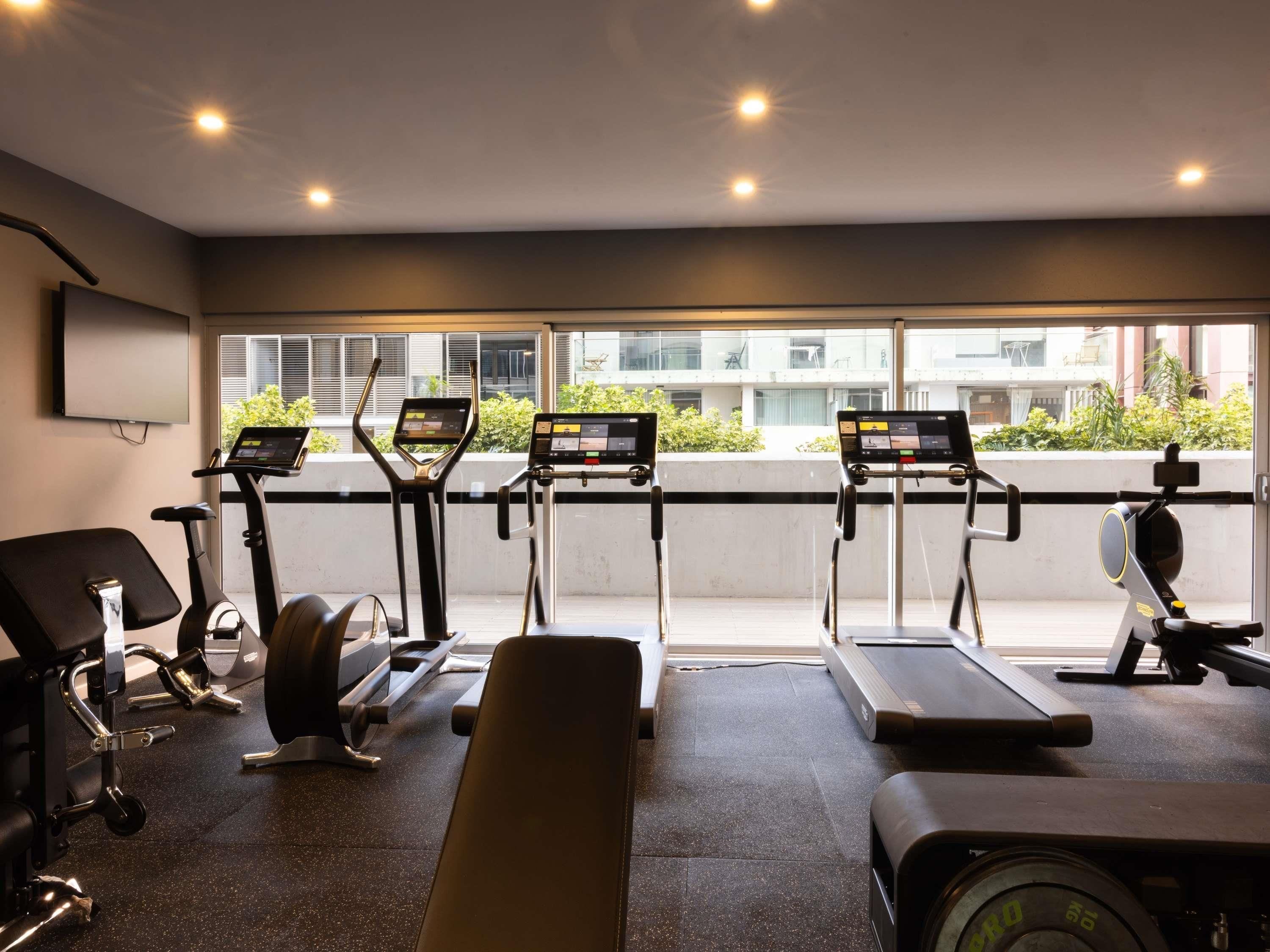 Un gimnasio con cintas de correr, bicicletas estáticas y máquinas de pesas.