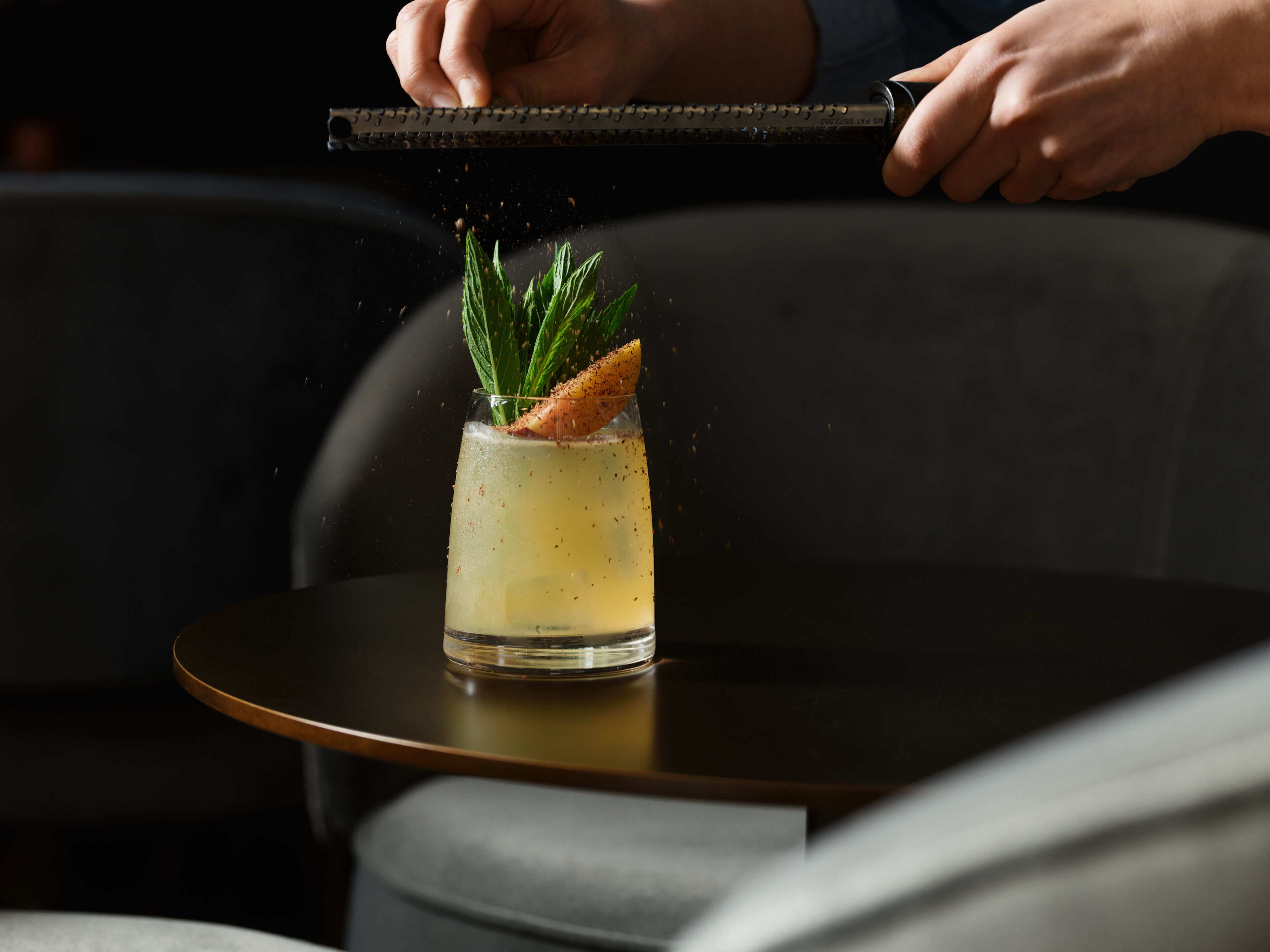A person pouring a drink into a glass on a table.