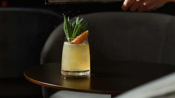 A person pouring a drink into a glass on a table.