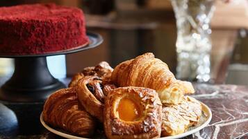 A plate of pastries and a red cake on a marble table.
