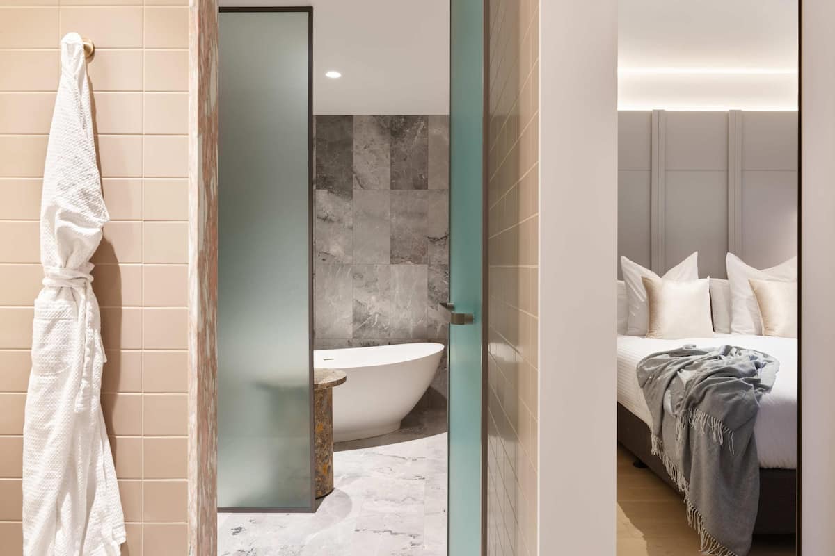 Ein modernes Badezimmer mit einer Badewanne, einer Duschkabine aus Glas und einem weißen Handtuch an der Wand.