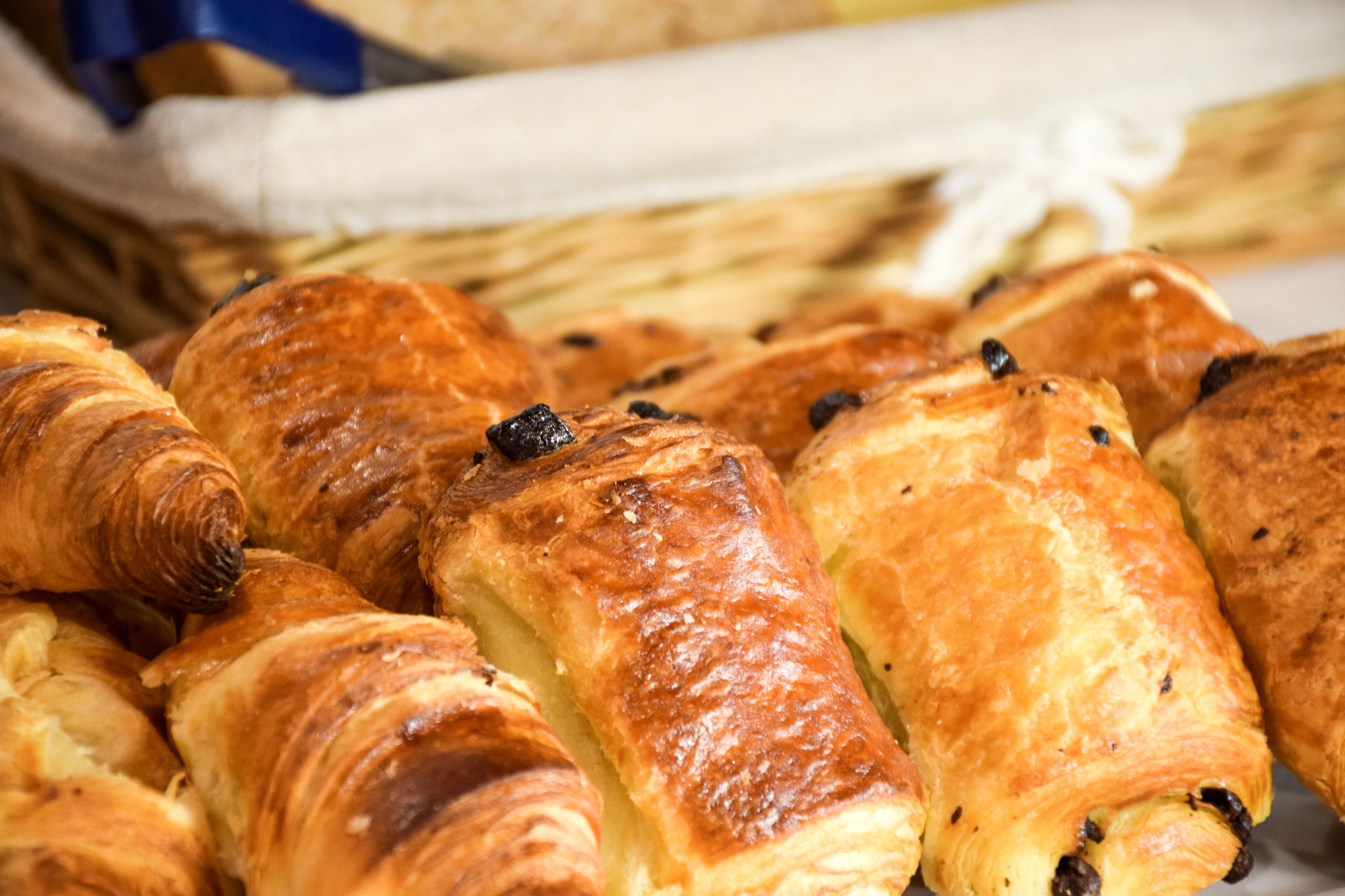 Ett urval av bakverk, inklusive croissanter och frallor, presenterade i en korg.