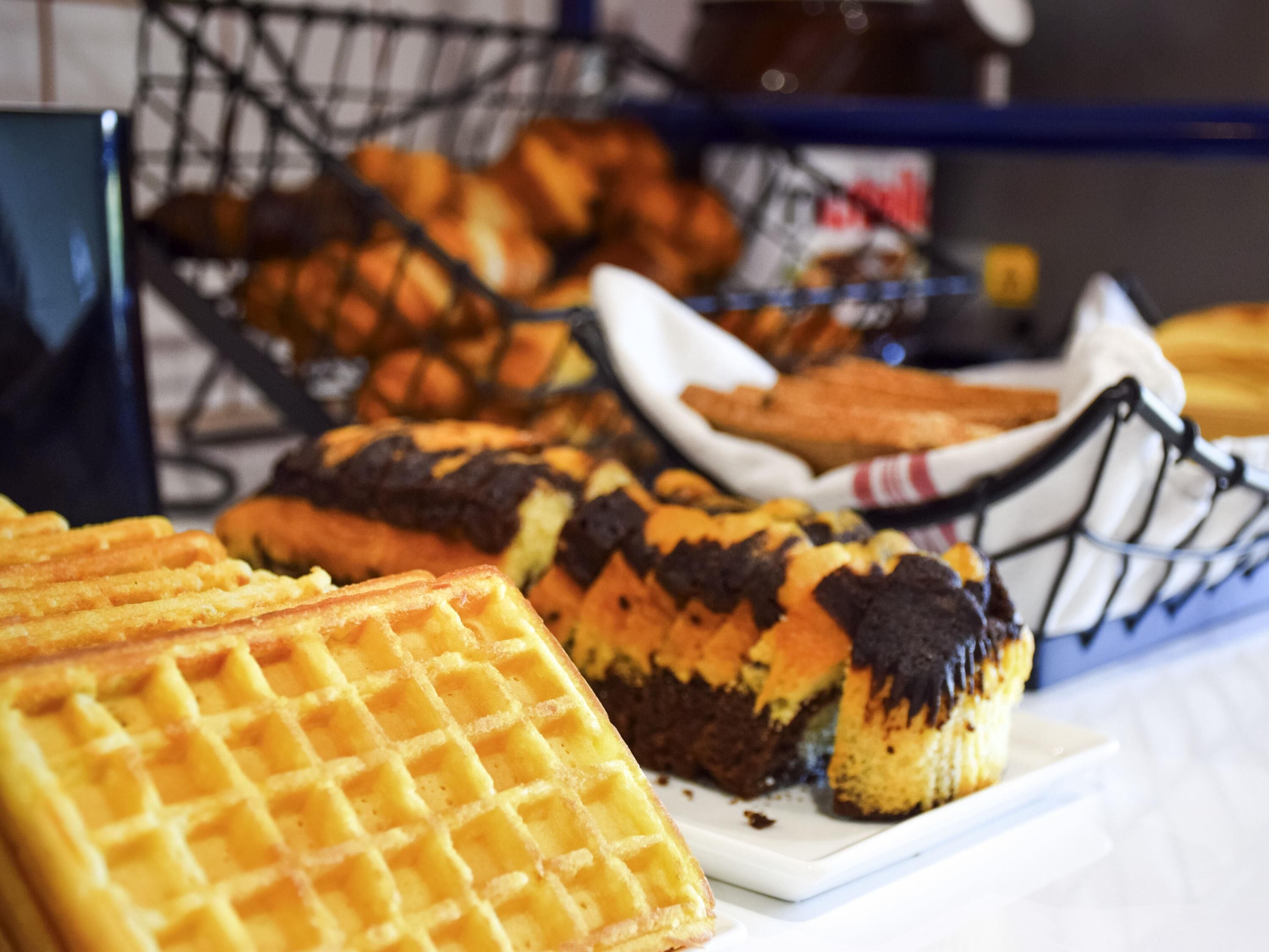 A variety of baked goods including waffles and pastries displayed in baskets.