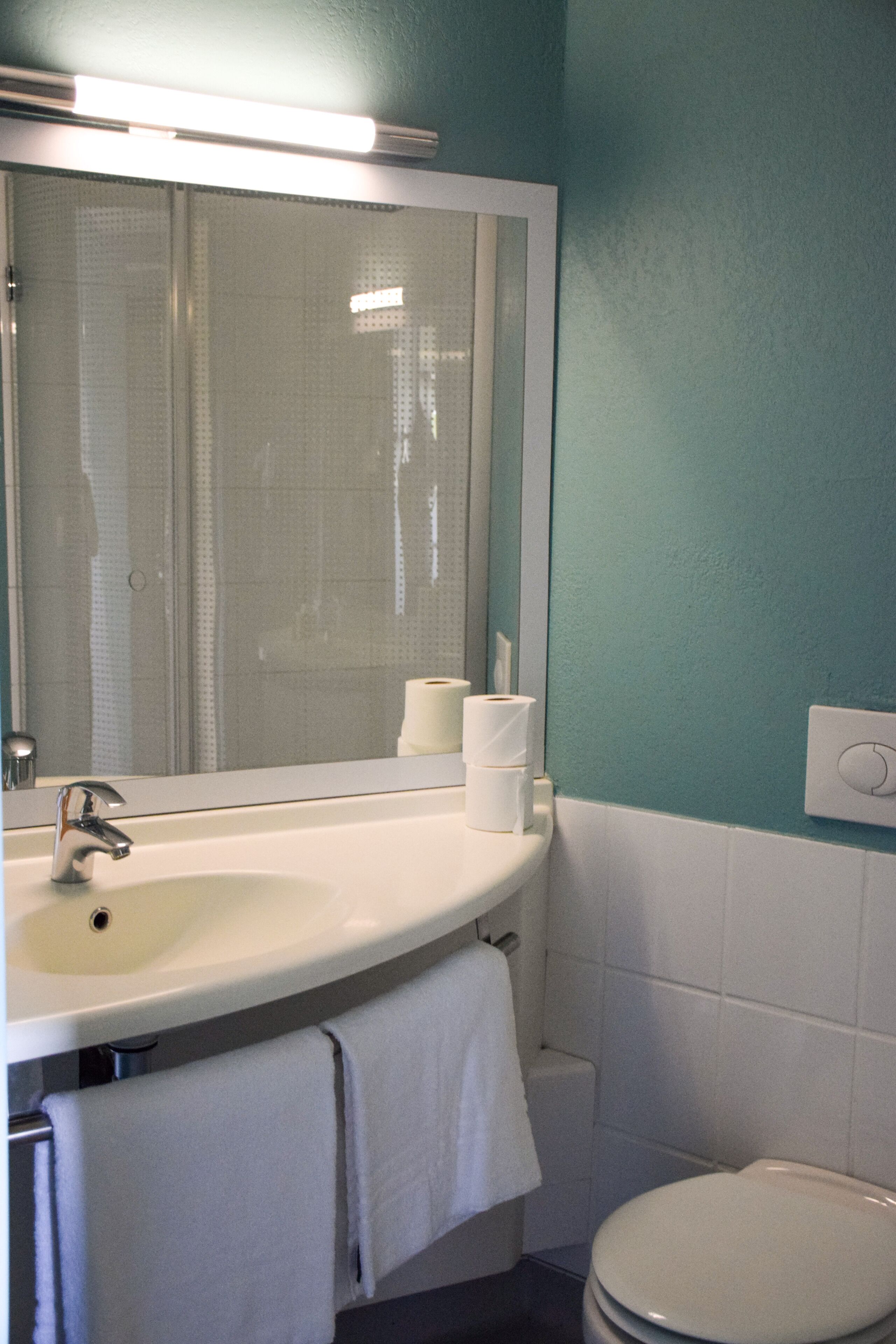 A bathroom with a white sink, a mirror, and a toilet.