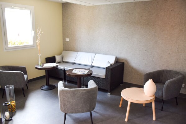 A modern lounge area with a sofa, two armchairs, a small round table, and a vase.