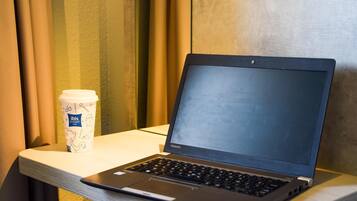Ein Toshiba Laptop auf einem weißen Tisch, neben ihm eine Kaffeetasse.