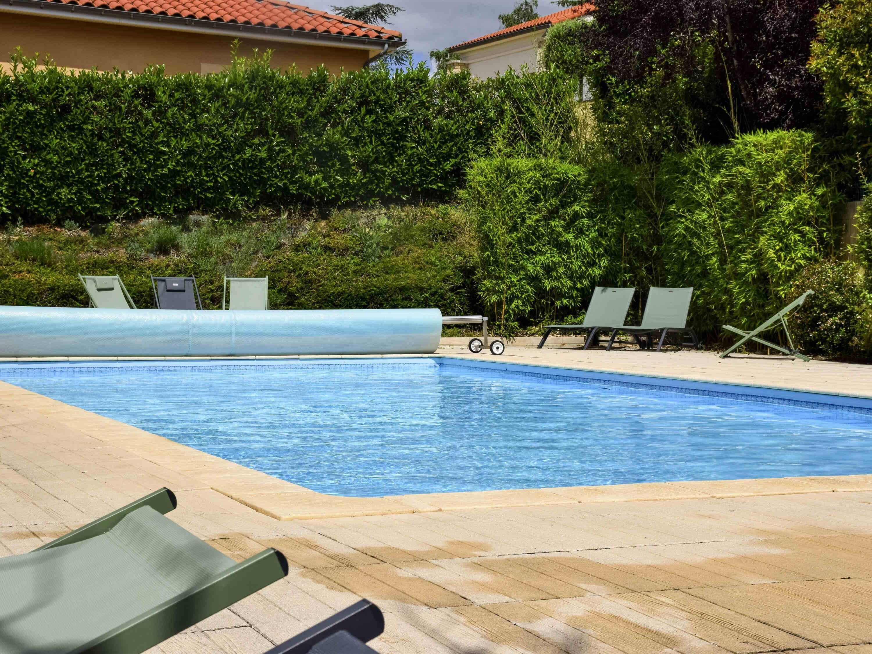 Una piscina con sillones de descanso y un tobogán de agua.