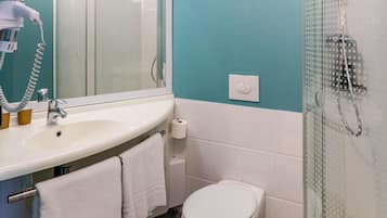 Une salle de bain équipée d’un lavabo, d’un miroir, d’un porte-serviettes, de toilettes et d’une douche.