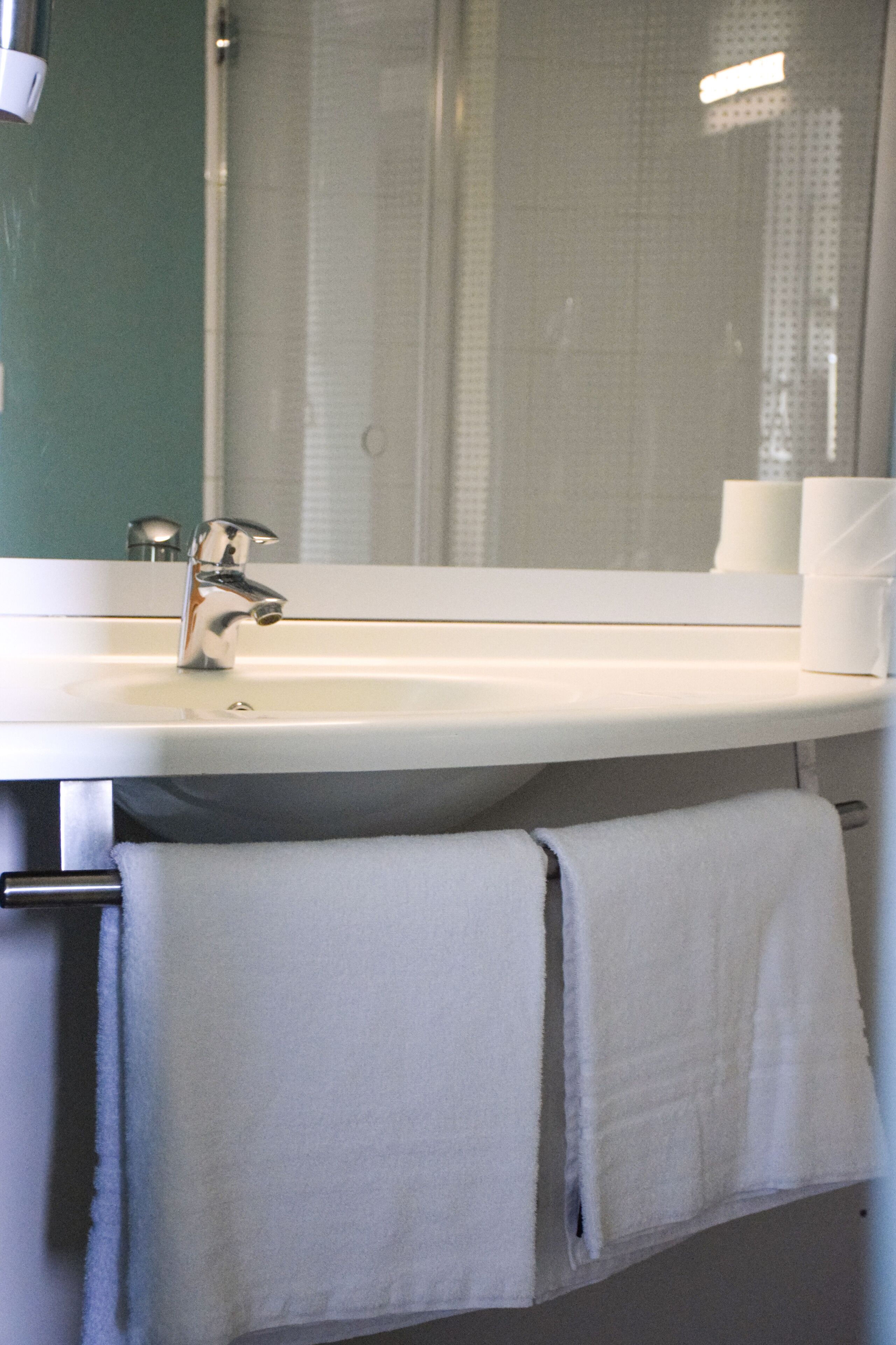 Un baño con un lavabo blanco, un espejo y un toallero.