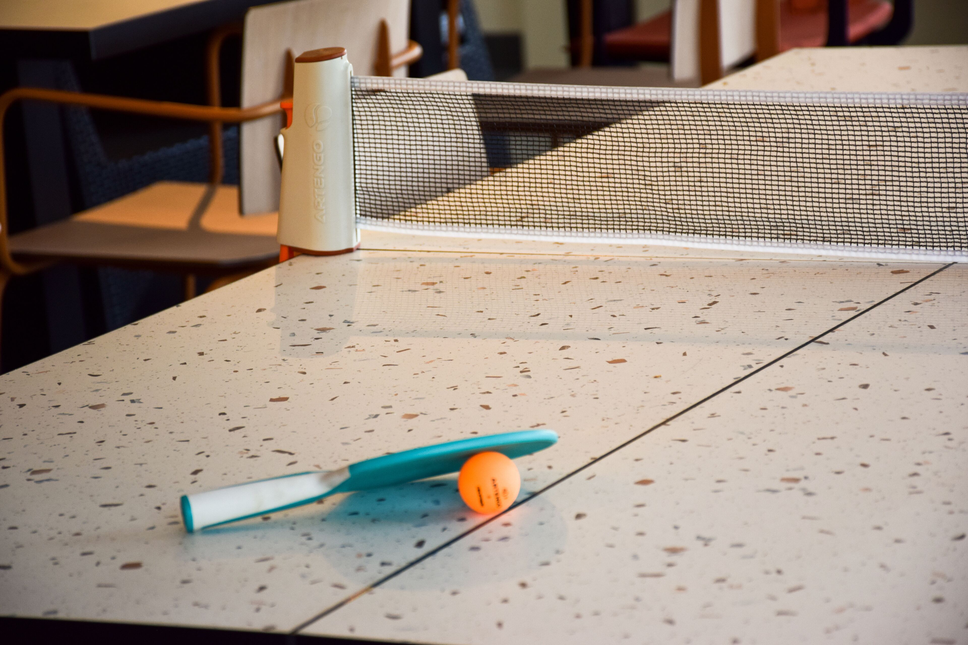 Una mesa de ping pong con una red, una pelota y una raqueta.