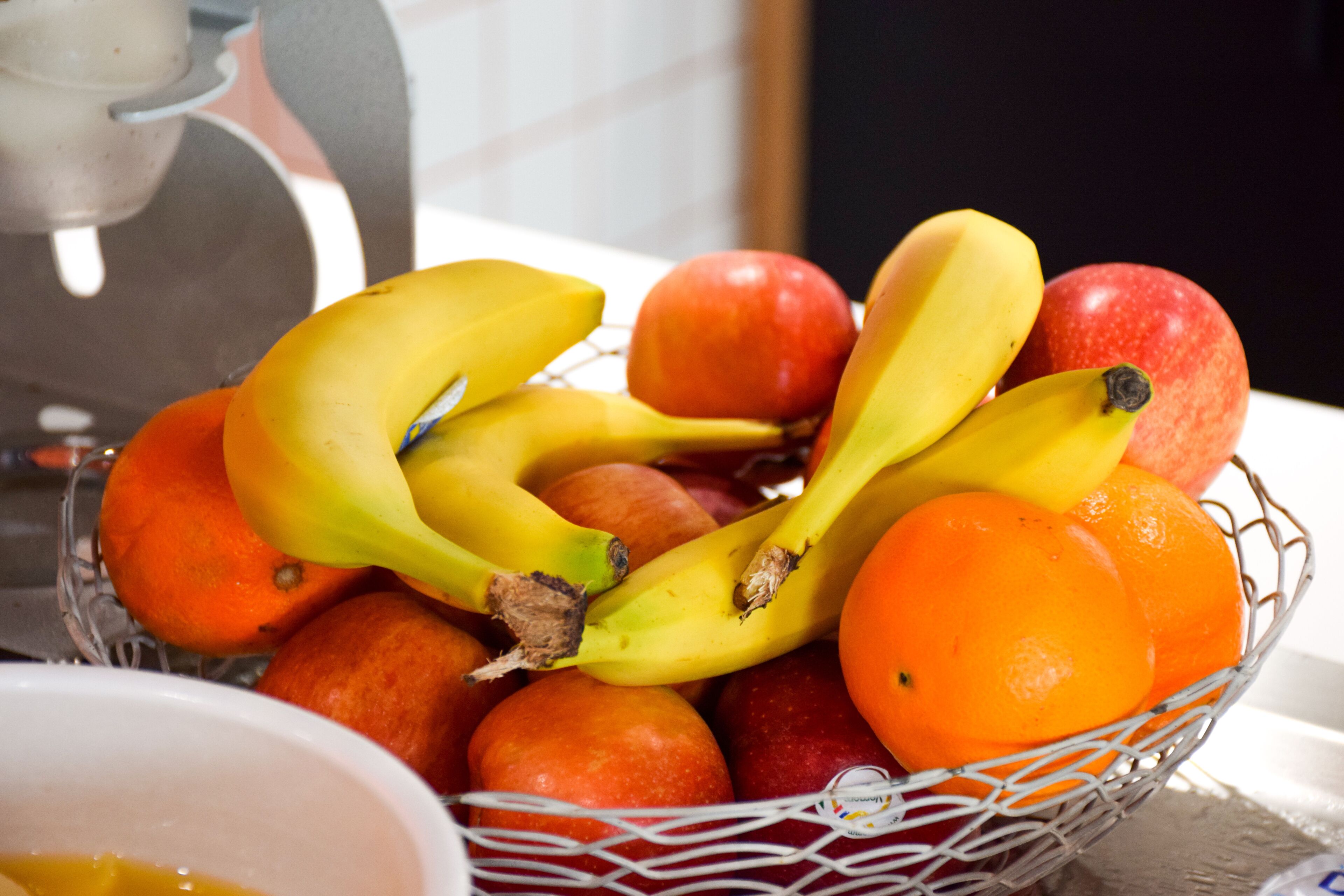 Una cesta de frutas con plátanos, manzanas y naranjas.