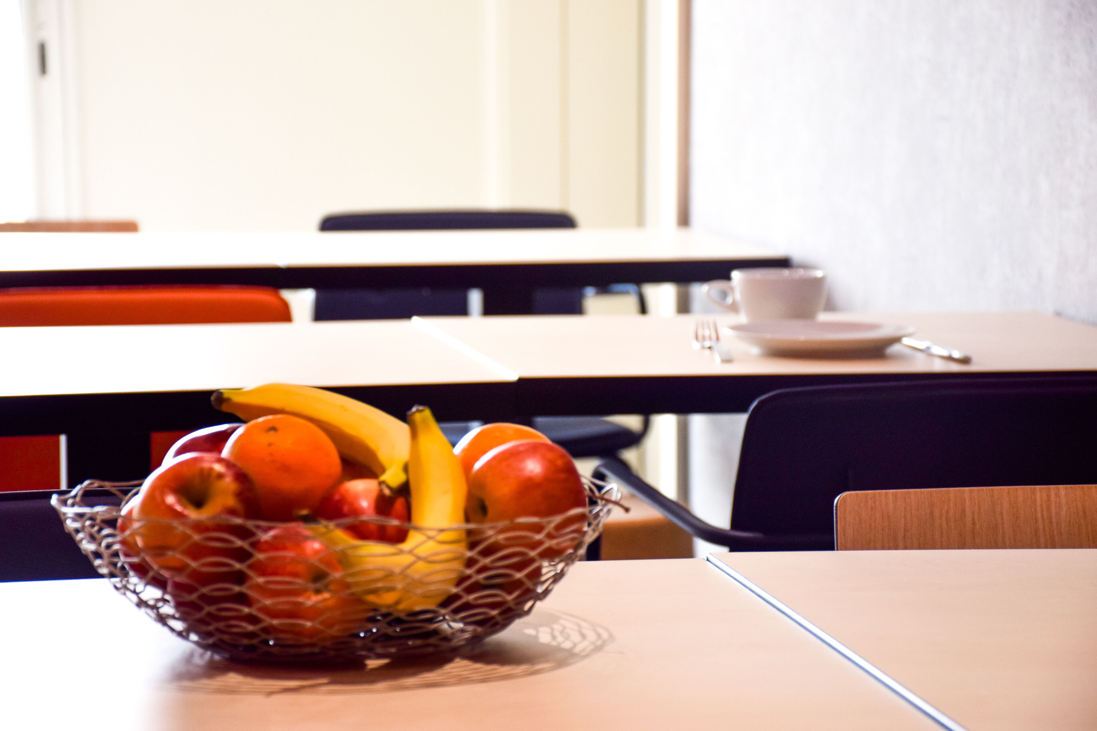 Une table à manger sur laquelle se trouve un panier de fruits contenant des pommes, des oranges et des bananes.