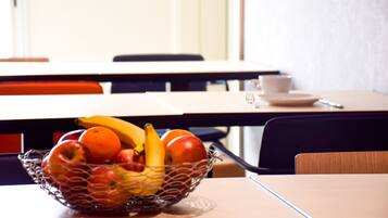 Une table à manger sur laquelle se trouve un panier de fruits contenant des pommes, des oranges et des bananes.