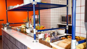 A buffet counter with various food items, a microwave, and a television in the background.