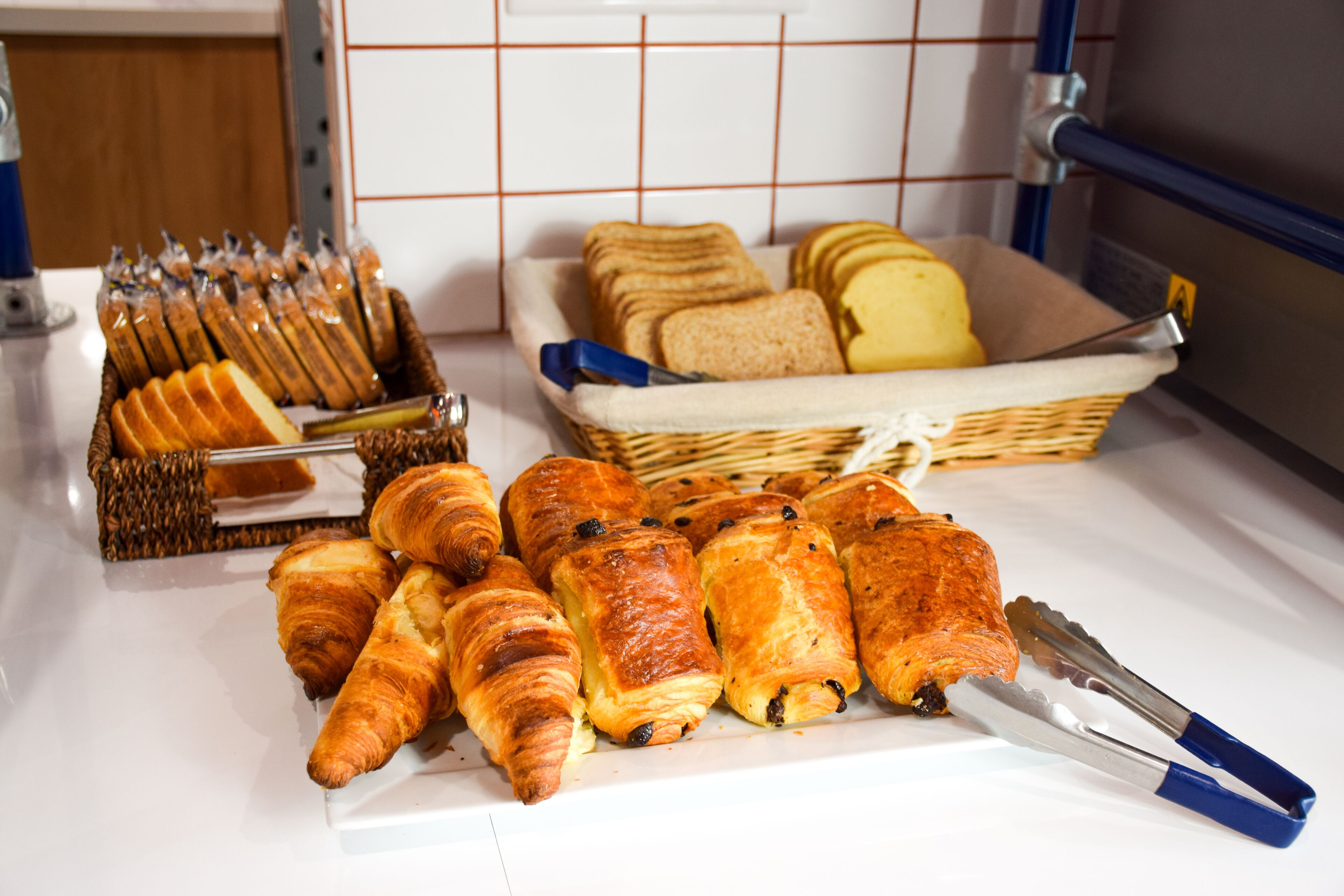 A variety of baked goods including croissants and bread, arranged on a kitchen counter.
