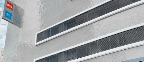 Un edificio moderno con un letrero que dice 'ibis budget' e 'ibis'. Presenta una fachada plana con líneas horizontales y grandes ventanales.