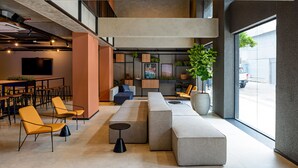 Ein stilvoller Lounge-Bereich mit Sitzgelegenheiten, einer großen Kübelpflanze und einem Fernseher an der Wand.