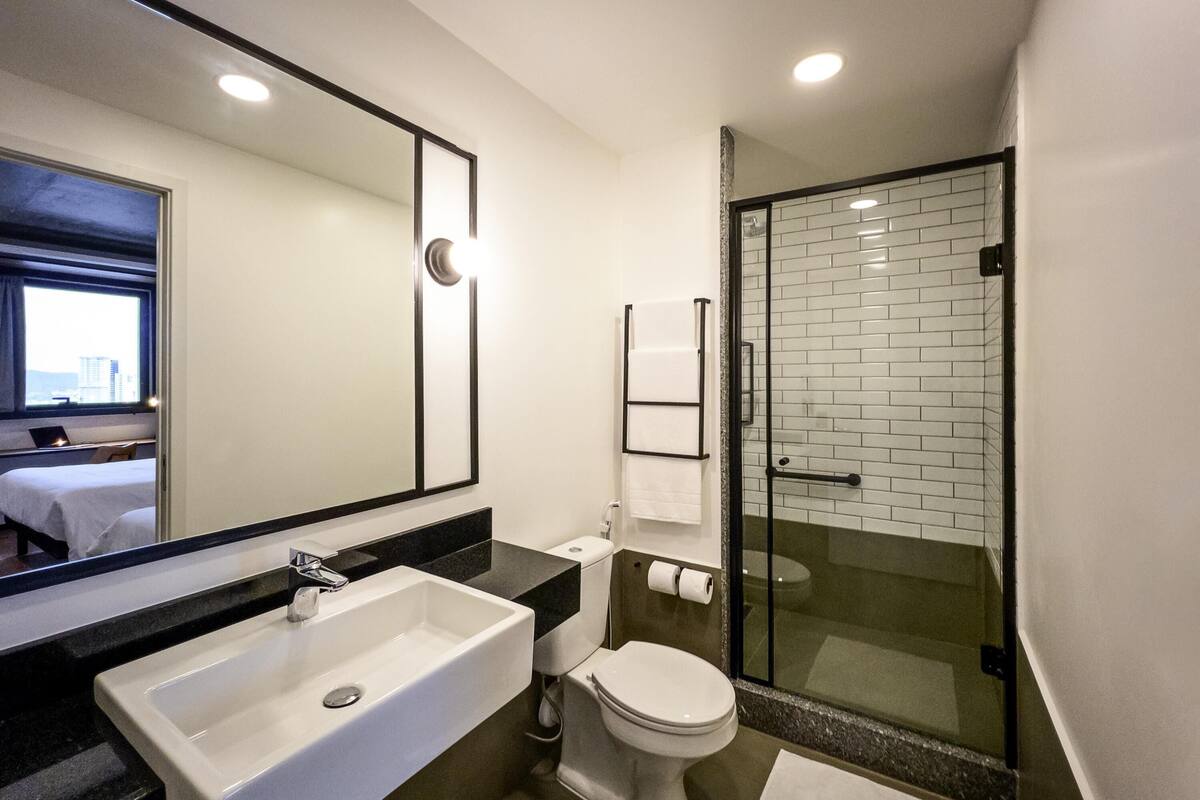 A modern bathroom with a large sink, toilet, and glass shower enclosure.