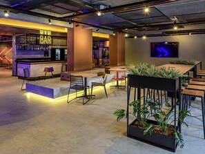 Eine moderne Bar mit Sitzgelegenheiten, einer Theke und einem Flachbildfernseher.