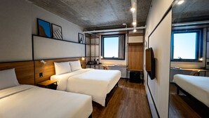 A hotel room with two beds, wooden flooring, a large window, and a television. - Ibis Plaza Balneario Camboriu (Balneário Camboriú)