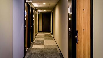 Corredor de hotel com piso carpete, portas numeradas 2254, 2256 e 2258, e uma porta de madeira no lado direito.
