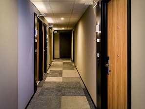 A hotel hallway with carpeted flooring, doors numbered 2254, 2256, and 2258, and a wooden door on the right. - Ibis Plaza Balneario Camboriu (Balneário Camboriú)