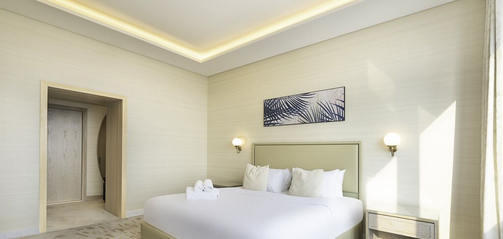 A hotel room with a large bed, two bedside tables, a headboard, and a wall-mounted artwork.