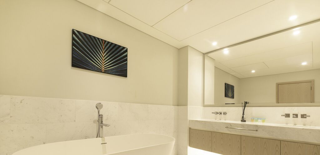 A modern bathroom with a freestanding bathtub, a large mirror, and a minimalist design.