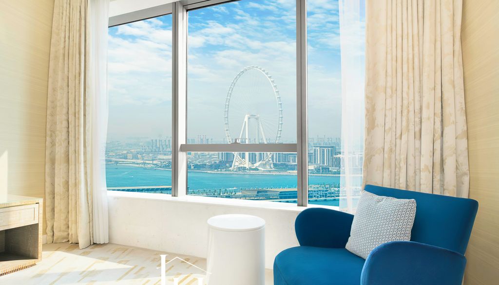 Una sala de estar moderna con vistas a una noria y al horizonte de Dubái.